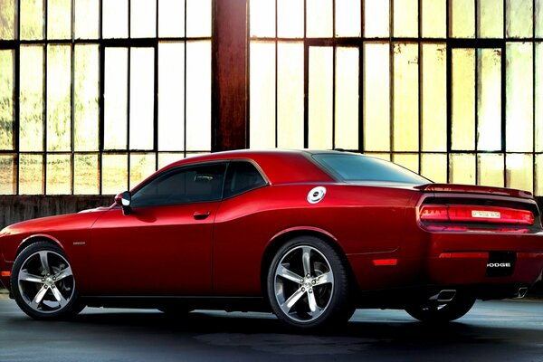 Red two-door challenger in a bright hangar