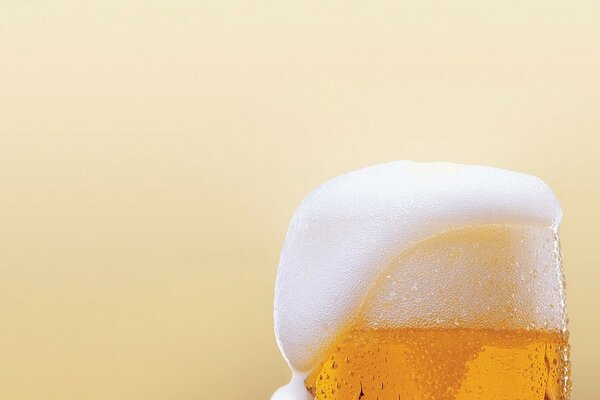 A glass of beer with a foam cap