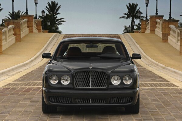 Чёрный Bentley на дороге из брусчатки, вид спереди