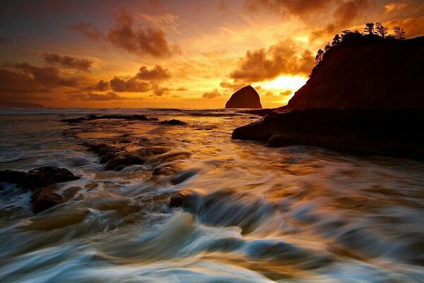 Ein atemberaubender Sonnenuntergang an der Küste spiegelt sich im Meer wider