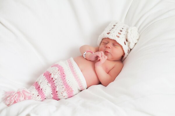 A little angel sleeps in a white hat