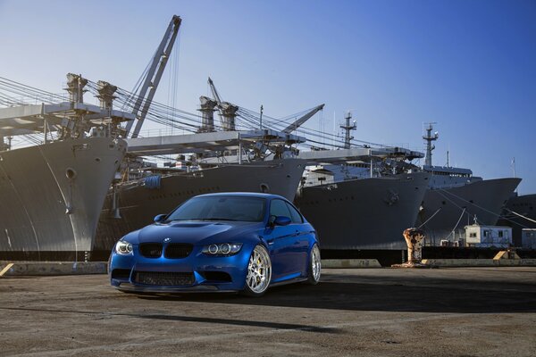 Niebieskie BMW na nabrzeżu przed skrzyniami