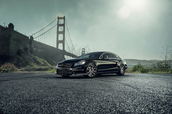 Une mercedes-benz noire se tient près du pont
