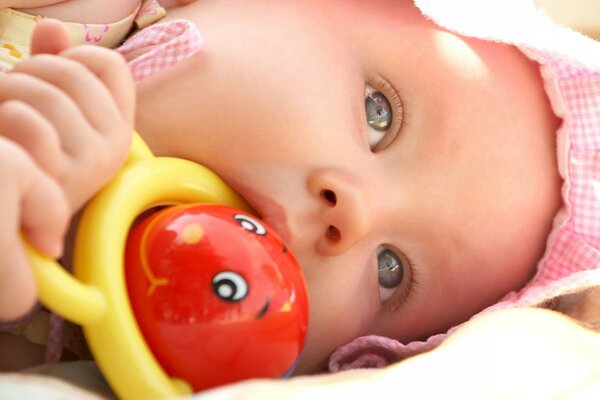 A child bites a red toy