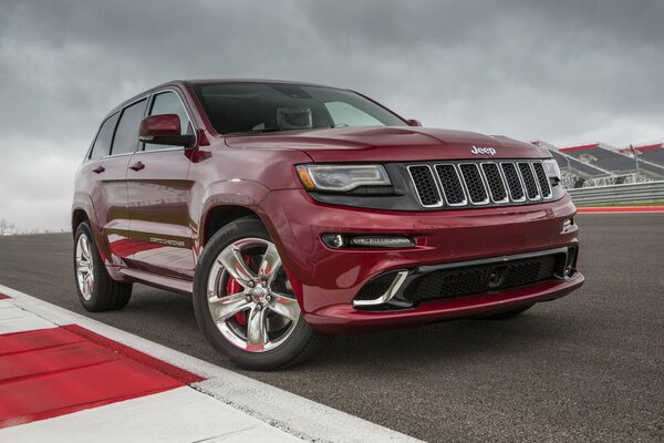 Rubinowy JEEP GRAND CHEROKEE stojący na torze wyścigowym