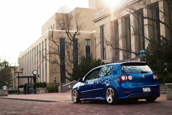 Blauer Volkswagen Golf fährt in der Stadt am Gebäude vorbei