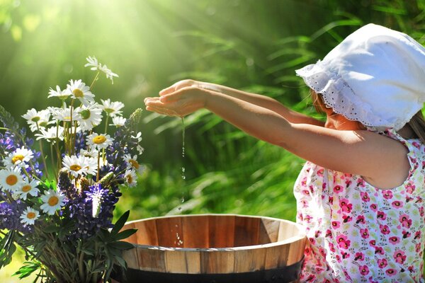 A girl pours water into a flower basin