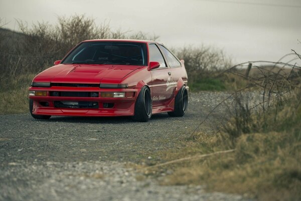Red old Toyota Corolla on rough terrain