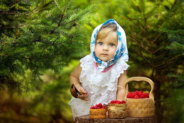 Mädchen mit einem Löffel im Wald mit Himbeeren in Körben