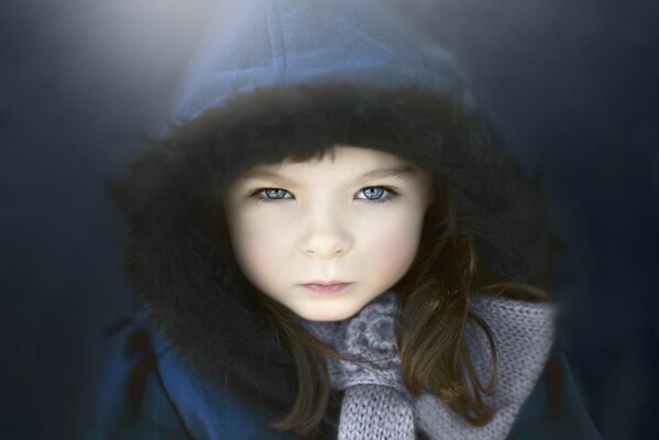 Portrait of a child with blue eyes in a blue hood