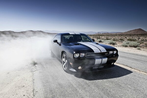 The black car rushes, leaving the dust to blow up