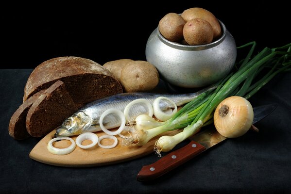 Potatoes in an iron pot with herring and onions on a cutting board