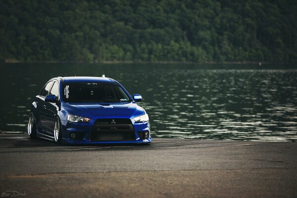 A blue mitsubishi car on the riverbank