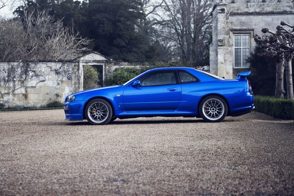 Blue nissan skyline near an old house