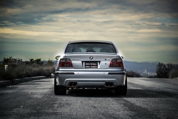 A silver BMW is driving on an asphalt road