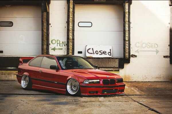 Ein roter getunter BMW e 36 steht auf dem Parkplatz. in der Nähe des Lagers