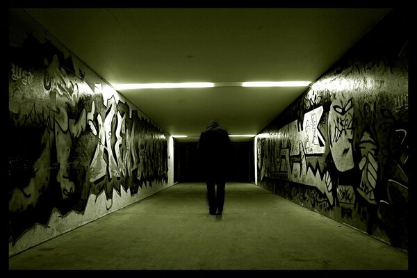 A man walking down the corridor in graffiti