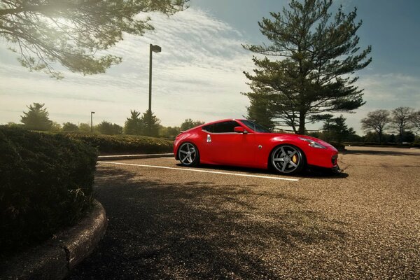 Red Nissan in the parking lot by the tree