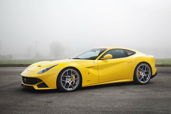 Yellow ferrari f12 in the fog on the asphalt