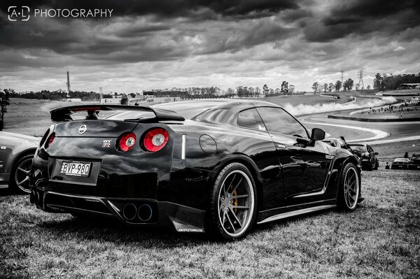 A black car on the side of the road against the background of clouds