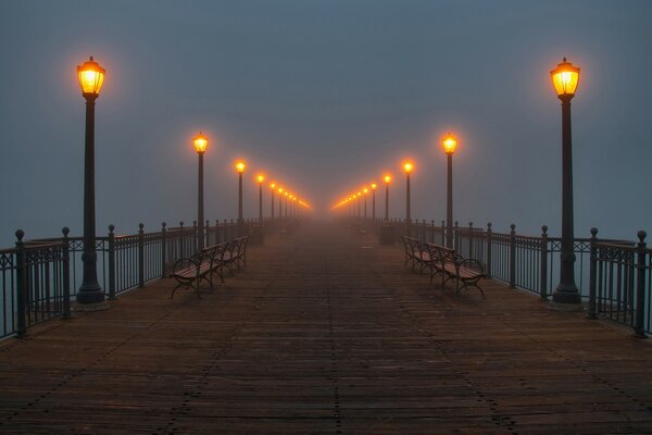 A deserted pier and burning lanterns in the fog