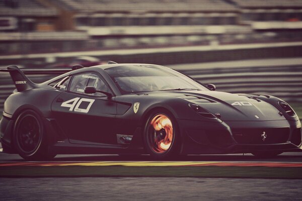 A black car is driving at speed on an auto track