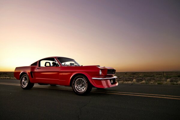 A picture of a red Ford Mustang car on the road