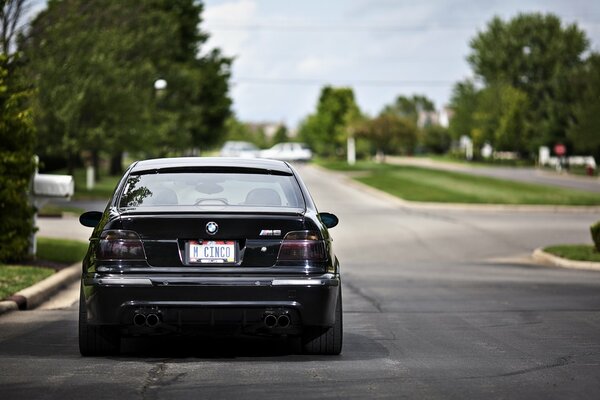 A black BMW is driving on the road