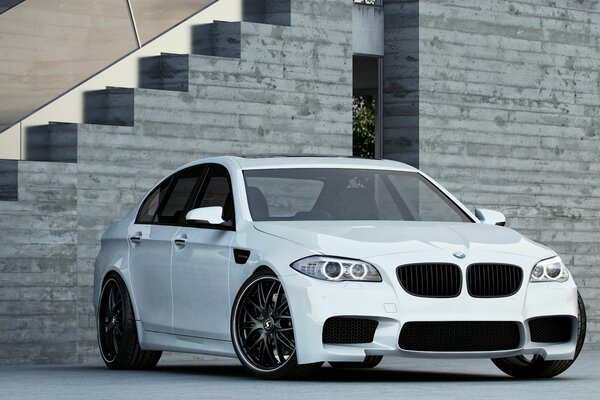 White bmw in daylight against the background of a gray building