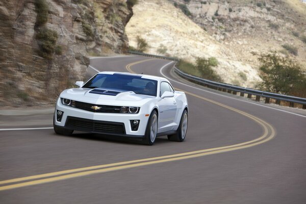 A white car is driving on the road outside the city