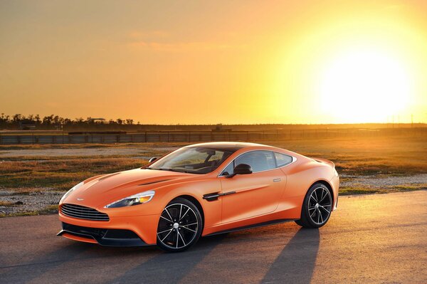 Aston martin orange sur fond de coucher de soleil