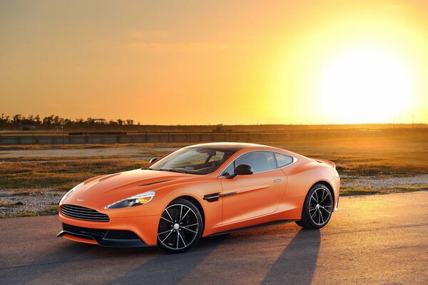 Aston martin arancione sullo sfondo del tramonto