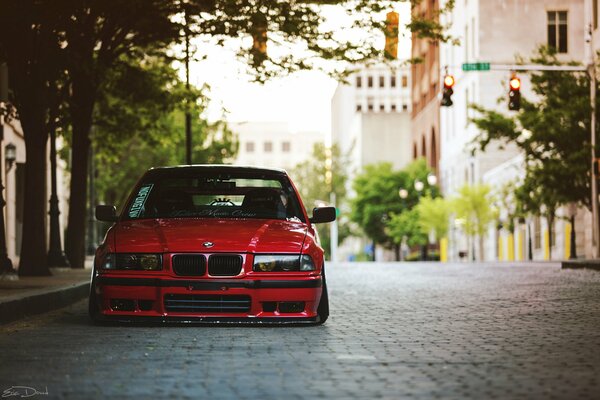 Red BMW e36 on grey paving stones