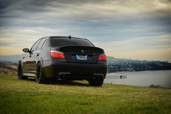 Black BMW on the grass by the lake