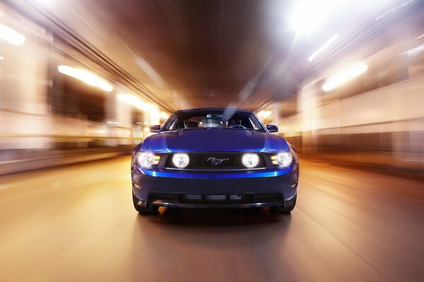Синий Ford Mustang едет на большой скорости