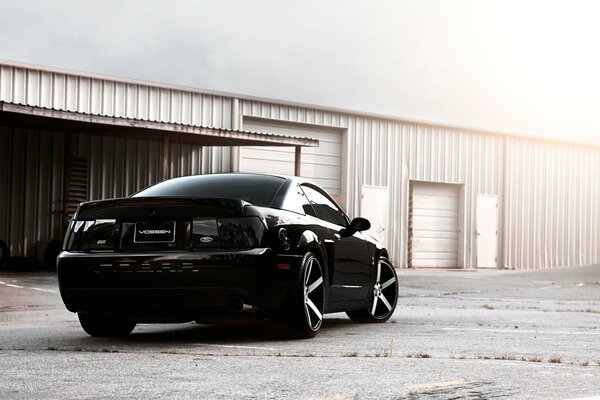 Black ford mustang on the background of the hangar