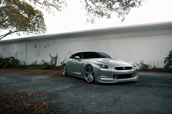 Silver Nissan on the background of a white fence