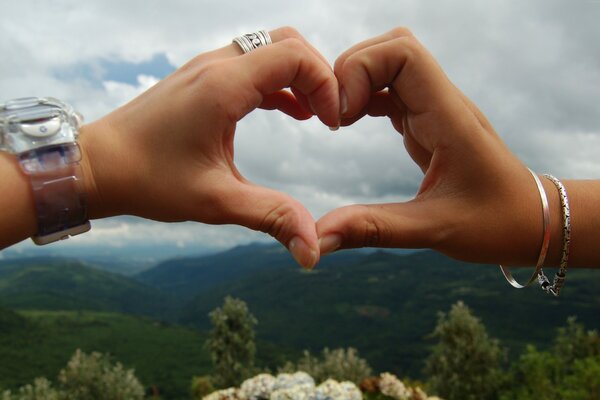 A heart with hands on the background of mountains