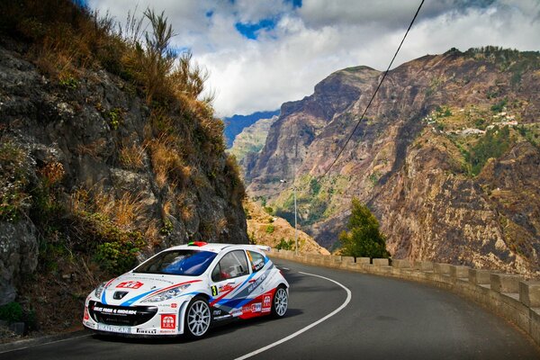 White peugeot on a turn on a mountain road in summer