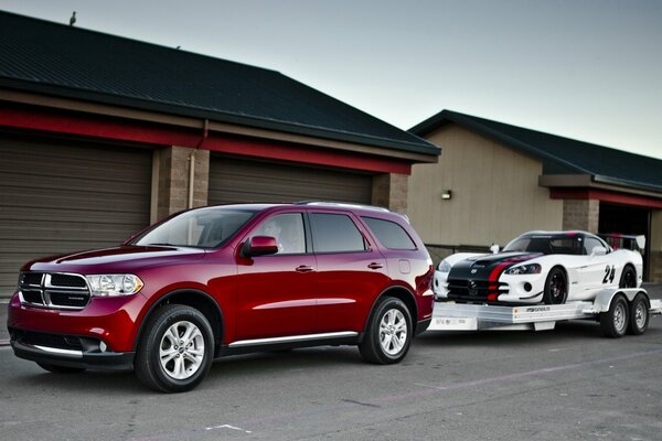 Dodge Durango y superdeportivo str10 en el fondo de las casas