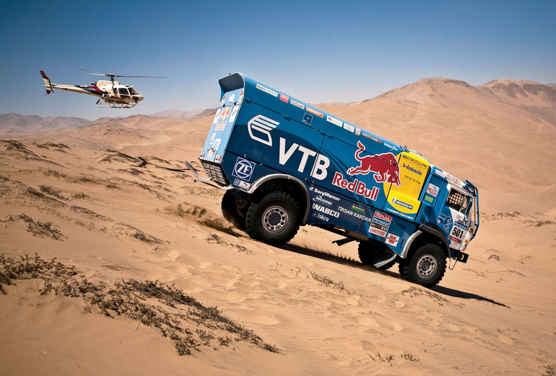 kamaz dakar rally azul toro rojo helicóptero vista lateral descenso coche auto arena duna