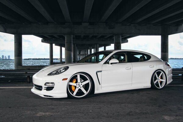 White tuned Porsche Panamera with beautiful discs, photo under the bridge