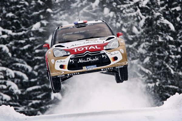 A rally car in flight against the background of a snowy highway