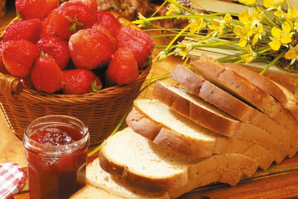 Brot mit Marmelade und einem Korb mit Erdbeeren in Blumendekoration