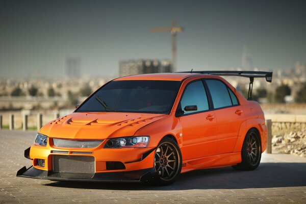 Orange mitsubishi lancer on the background of the city