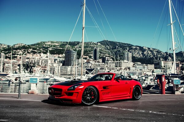 Red Mercedes on the background of buildings and yachts