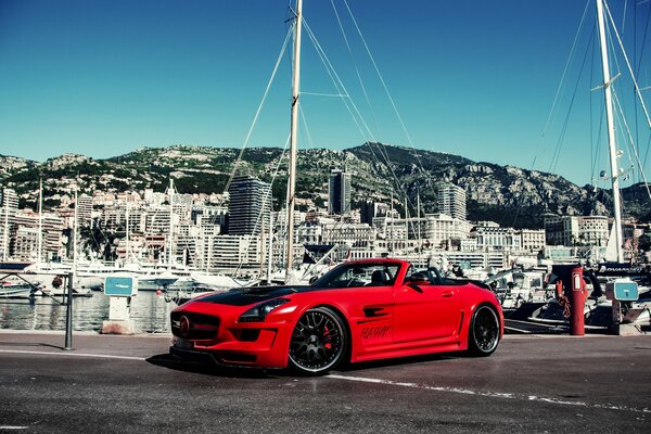 Mercedes rossa sullo sfondo di edifici e yacht