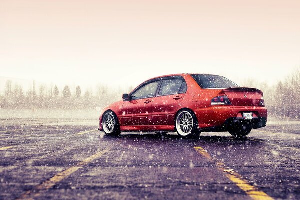 Arancione Mitsubishi Lancer evoluzione in inverno. Nevica