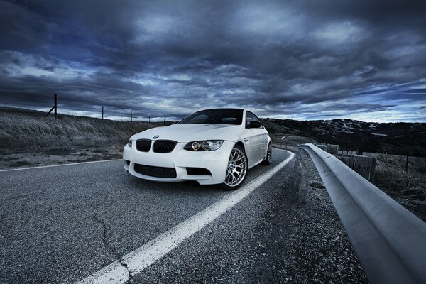 Weißes BMW-Auto auf dem Hintergrund von Wolken und Straßen