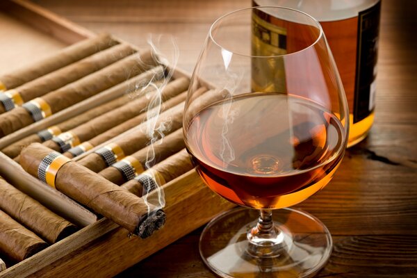Ein Glas Cognac und eine entzündete Zigarre
